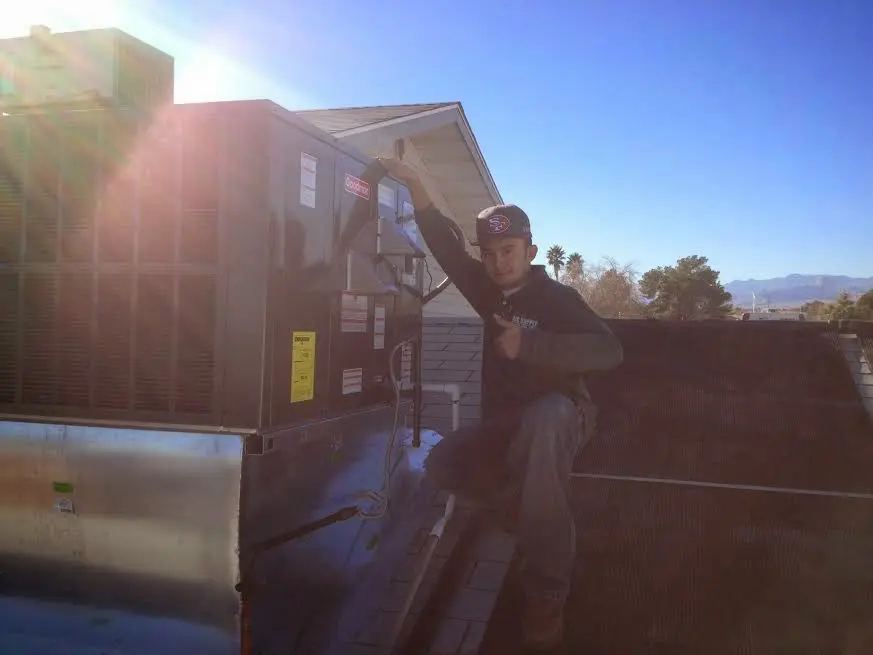 HVAC technician performing AC Tune-Up on a rooftop unit in Ogden