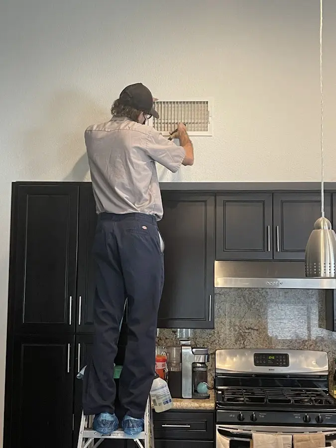 Technician inspecting an air vent during HVAC service in Ogden